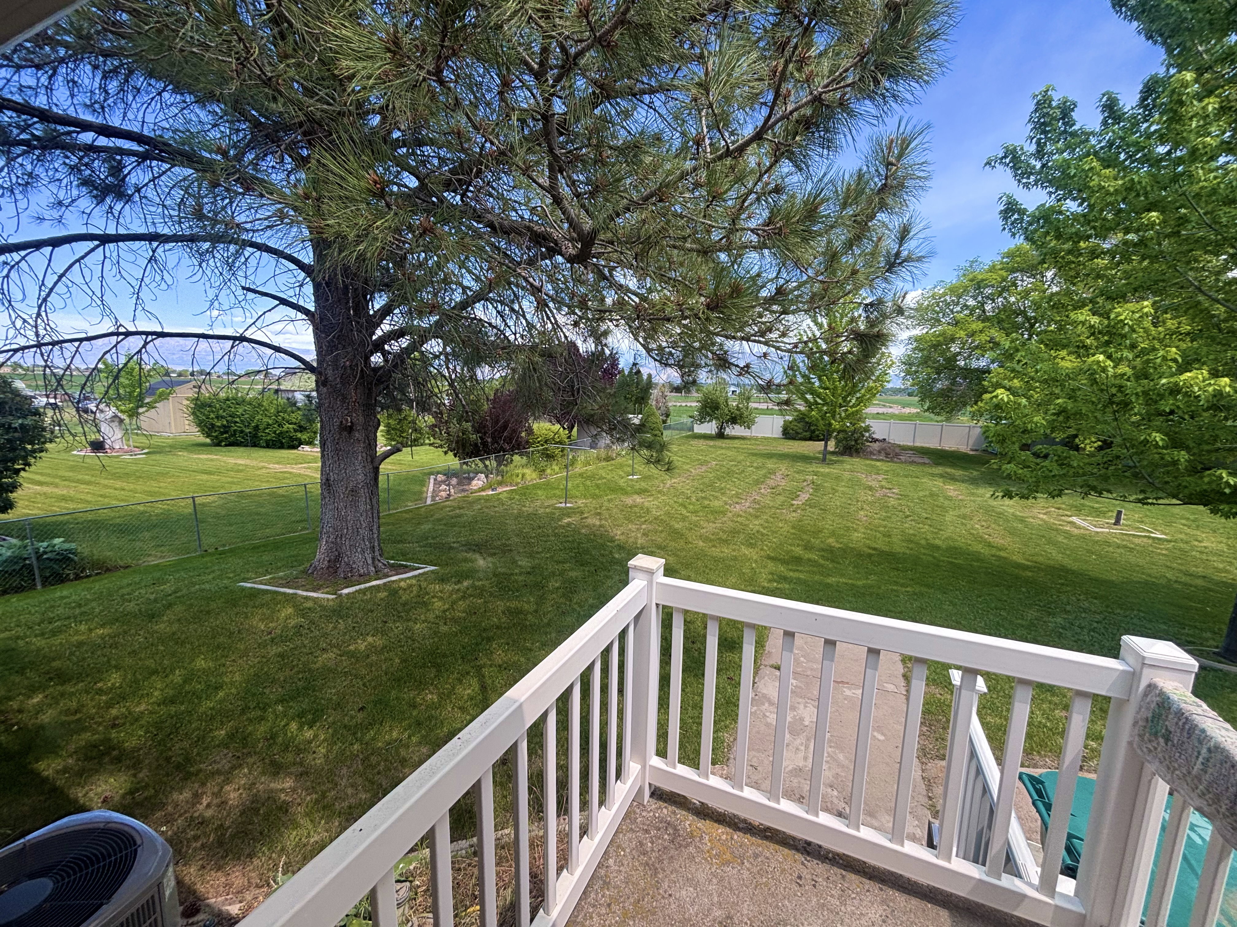 Expansive outdoor space featuring a large grassy lawn and mature trees