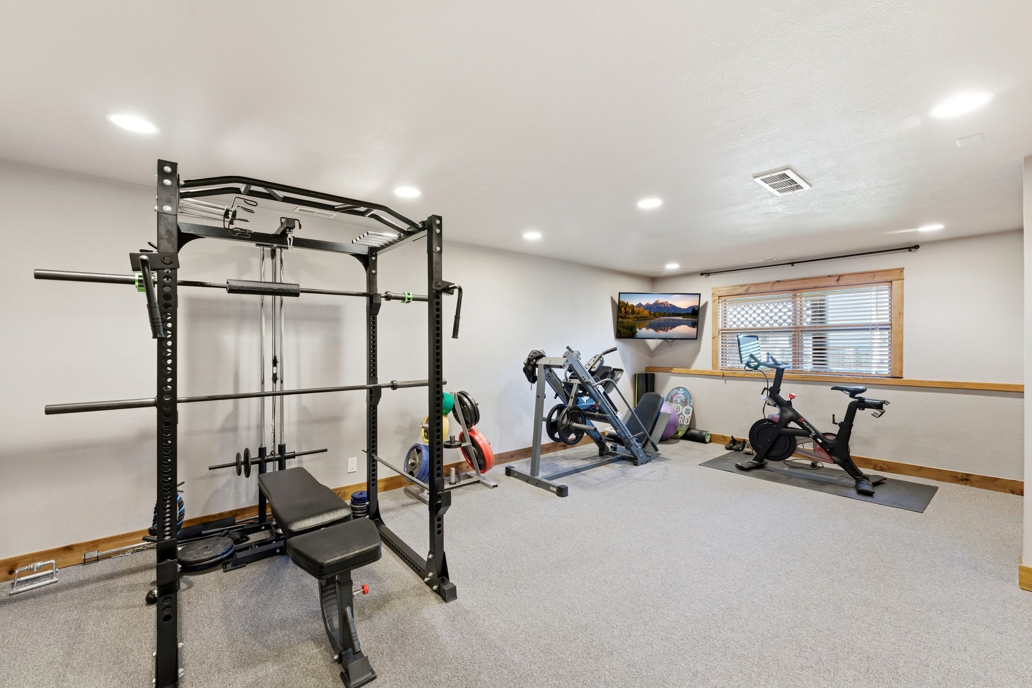 Versatile room featuring recessed lighting, light gray carpet, and a window with wood trim