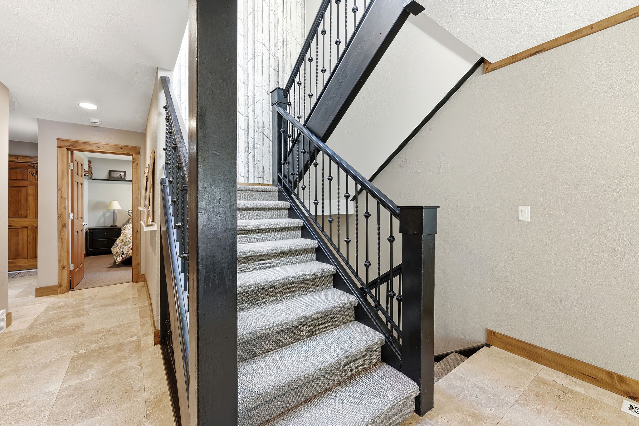 Carpeted staircase with wrought iron balusters and dark wood newel posts