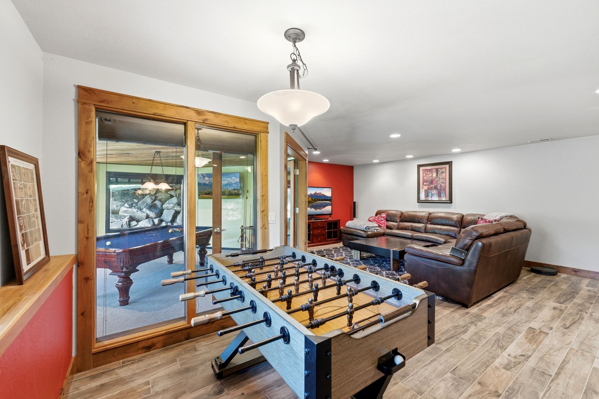 Spacious recreation room featuring wood-finish flooring, recessed lighting, and a prominent game table