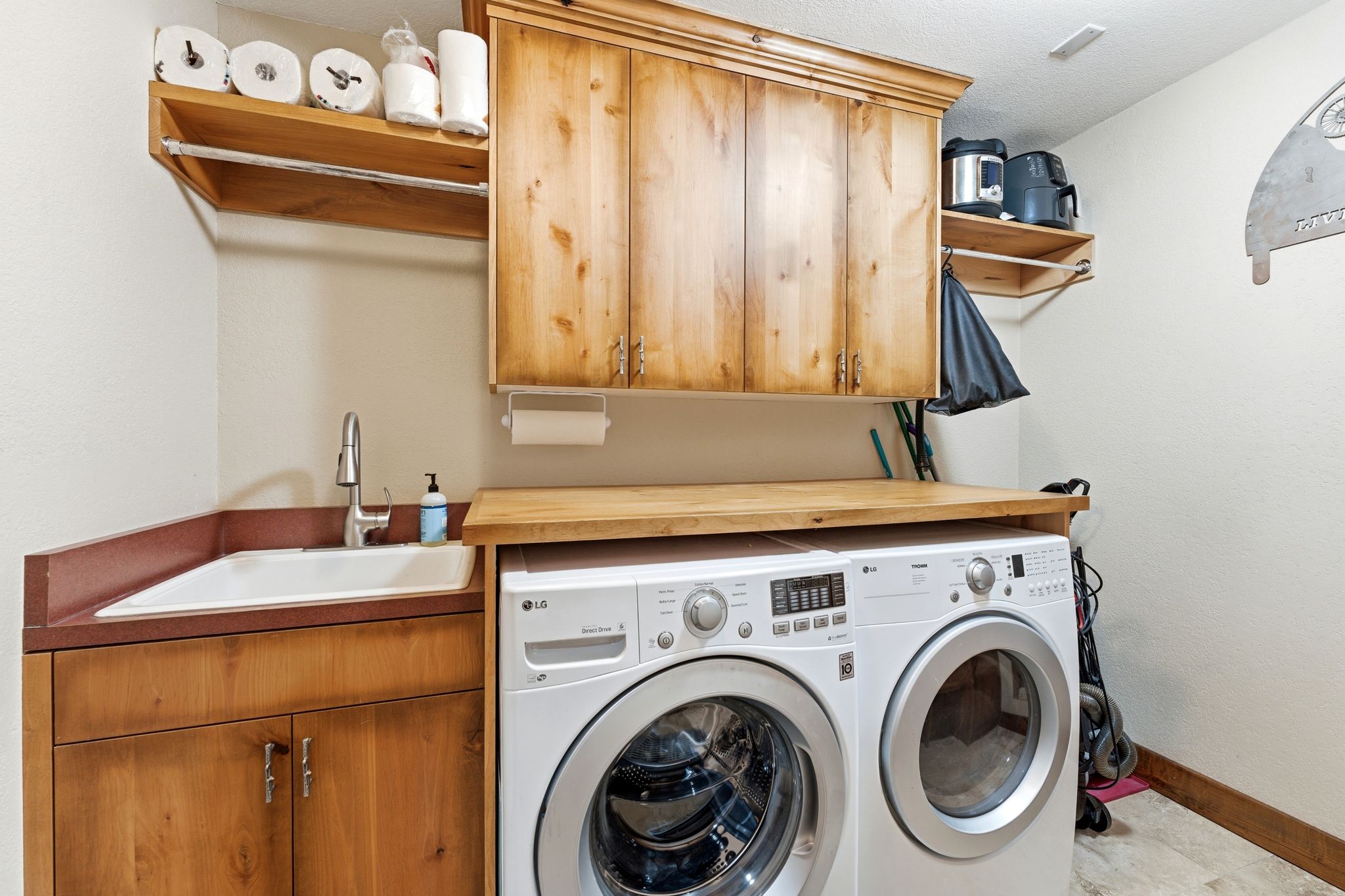 Functional utility space featuring a built-in sink with a gooseneck faucet, ample wood cabinetry, and an integrated wood-finish countertop