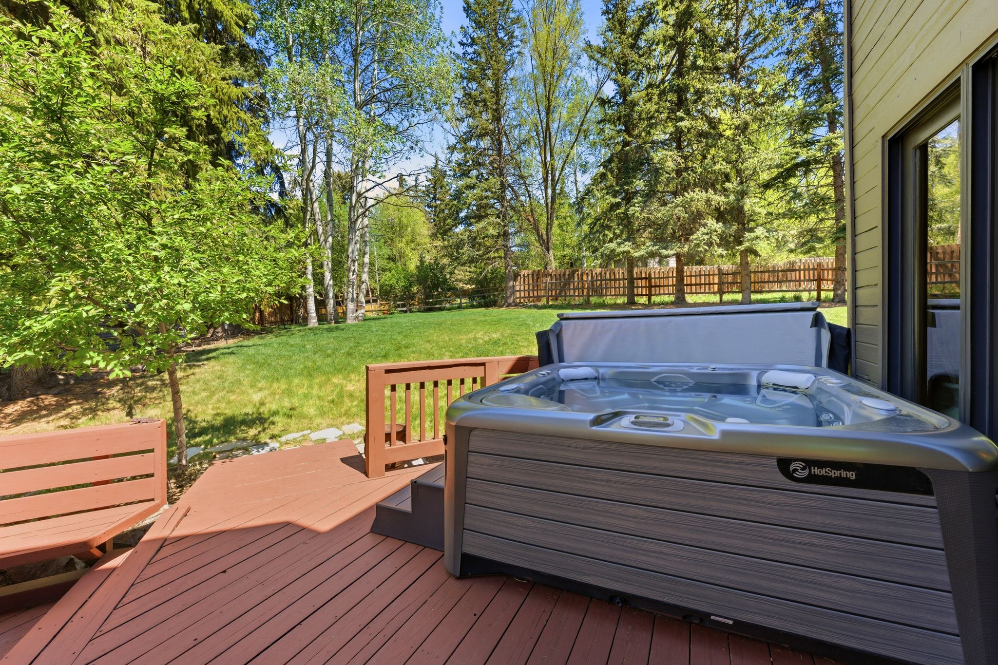 Expansive wood deck featuring a built-in bench and hot tub