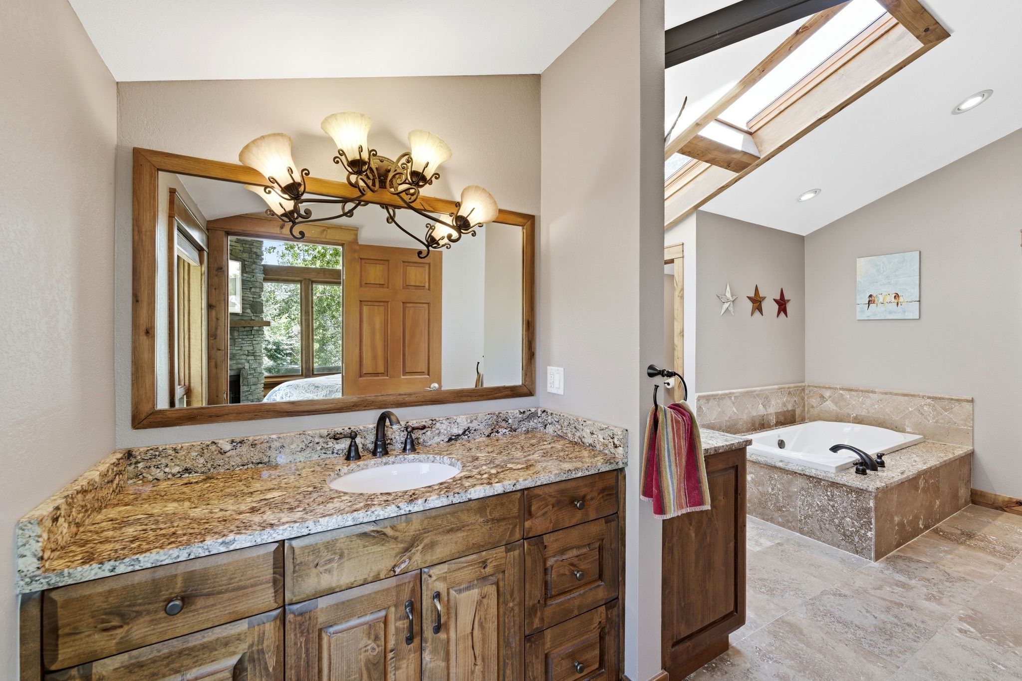 Bathroom featuring a rustic wood vanity with a granite countertop and undermount sink, bronze-finish faucet, and coordinating wood-framed mirror