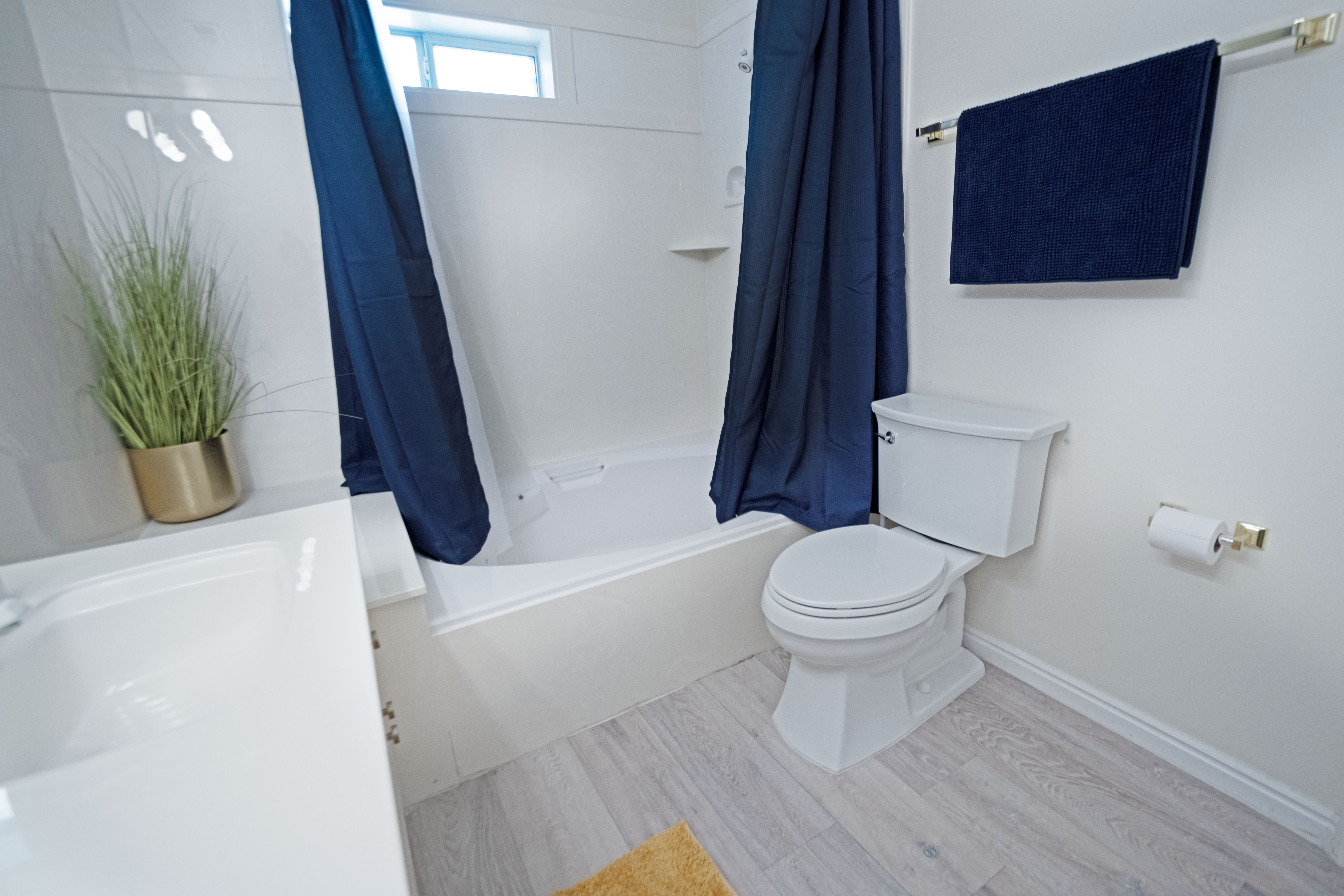 Primary bathroom featuring a white tub and shower combination, a white toilet, light wood-finish flooring, and white walls