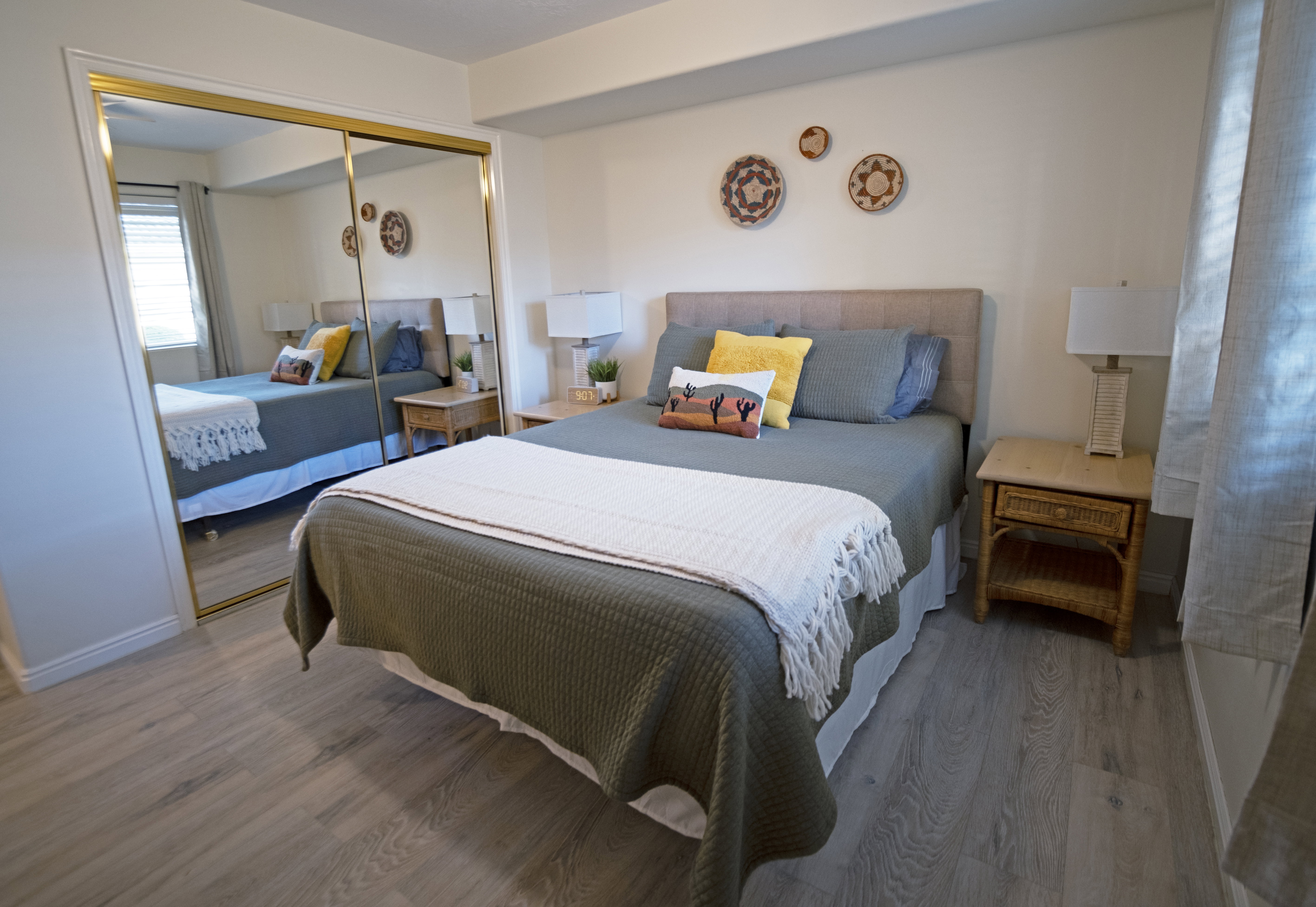 Spacious sleeping area featuring wood-finish flooring, a neutral color palette, and a window with blinds