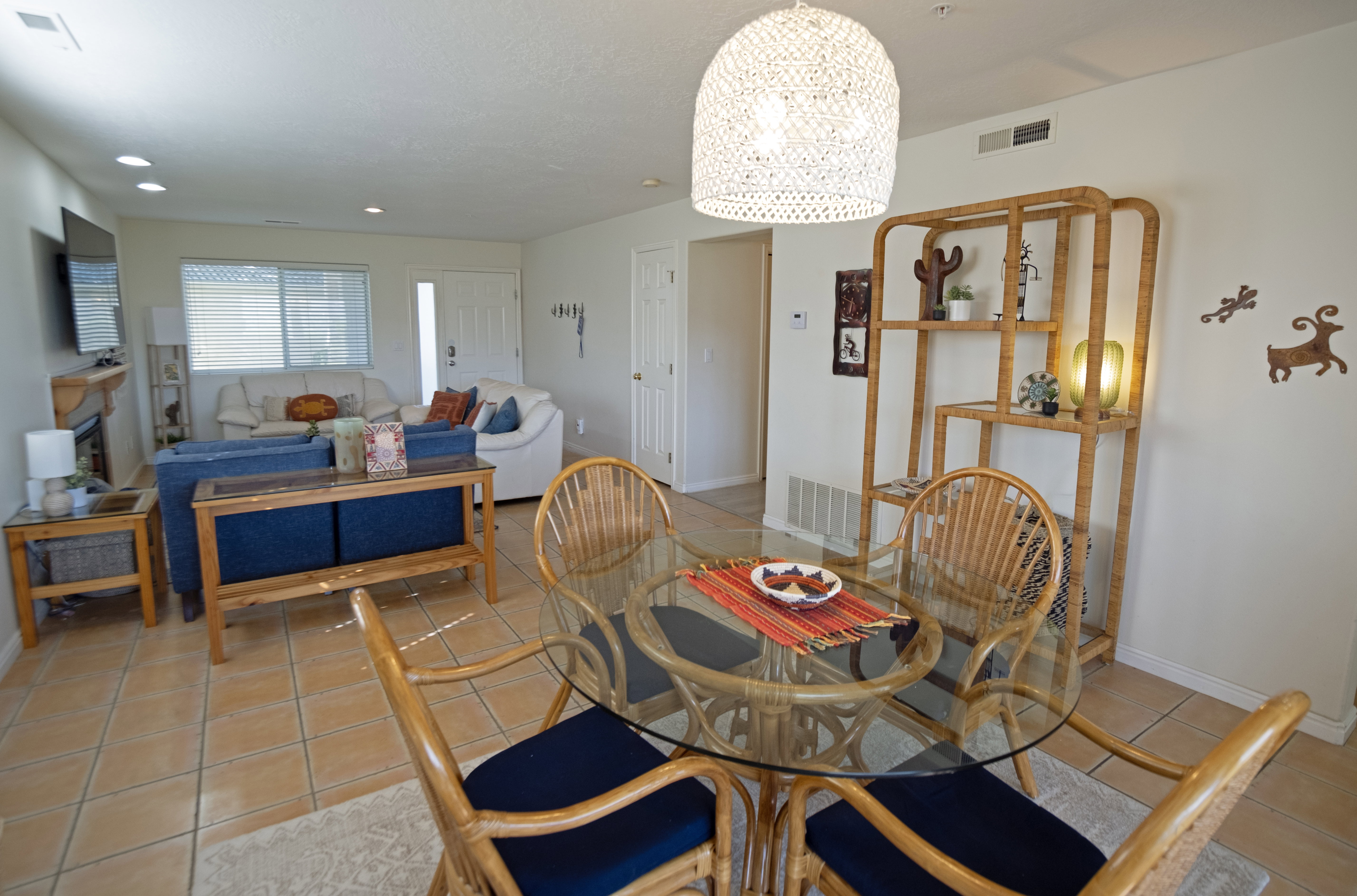 Open concept living and dining area featuring tile flooring, a glass-top dining table, and a decorative shelving unit