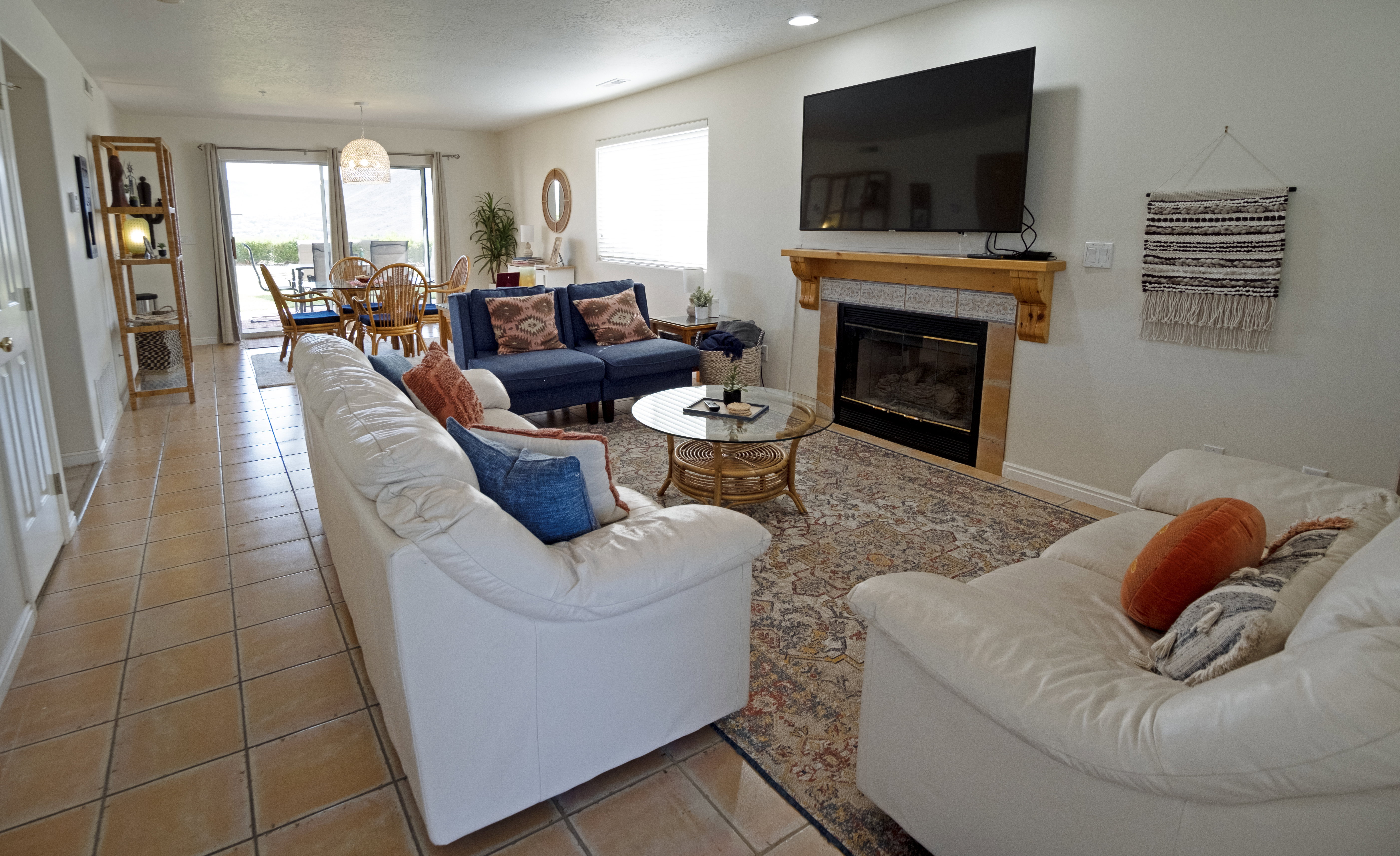 Living area with tile flooring throughout, a gas fireplace featuring a wood mantel, and sliding glass doors leading to the exterior