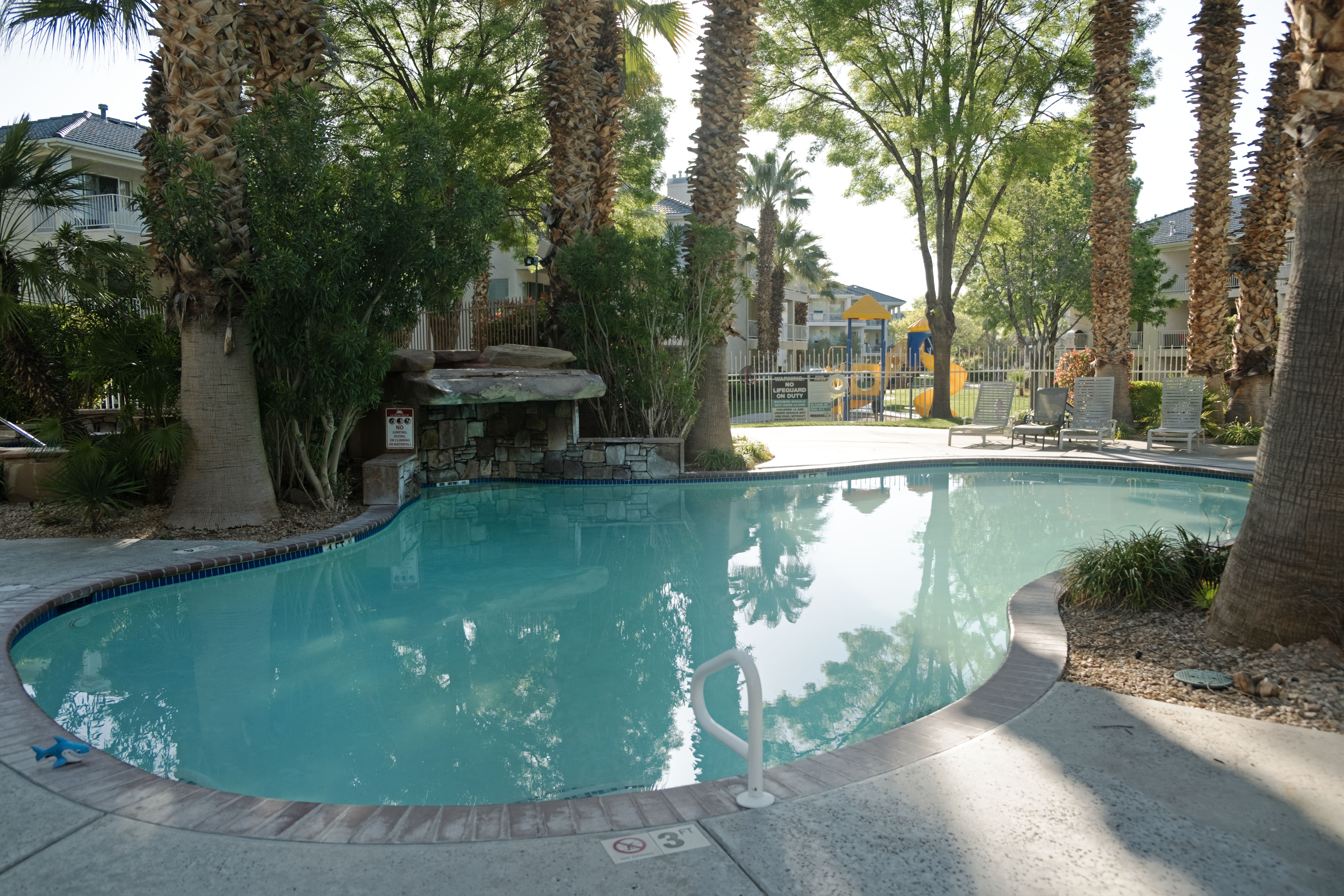 Resort-style swimming pool featuring a curved design and integrated waterfall
