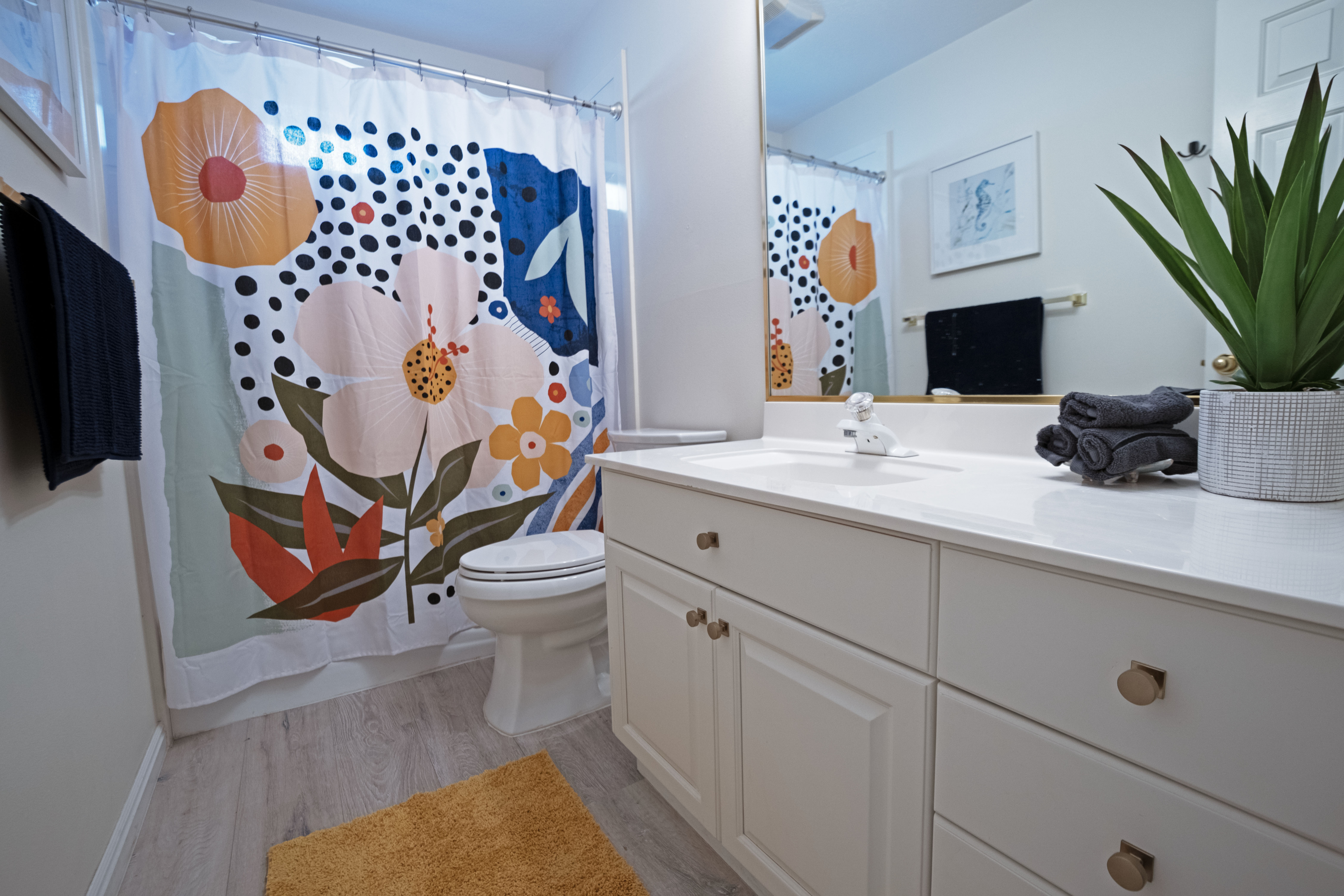 Bathroom vanity featuring a white countertop, an integrated sink, and white cabinetry with round brass hardware