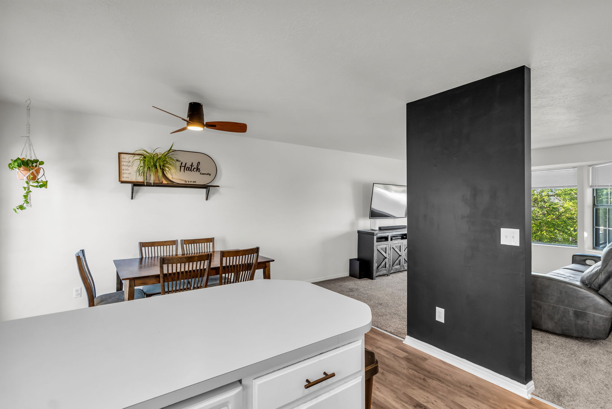 Open-concept dining area with a ceiling fan light fixture and wood-finish flooring extending into the living space