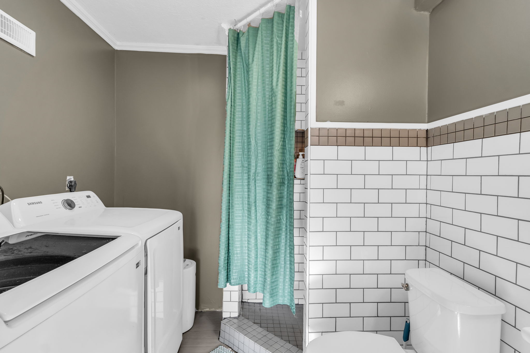Full bathroom featuring white subway tile, a tiled shower surround, and a coordinating wall color