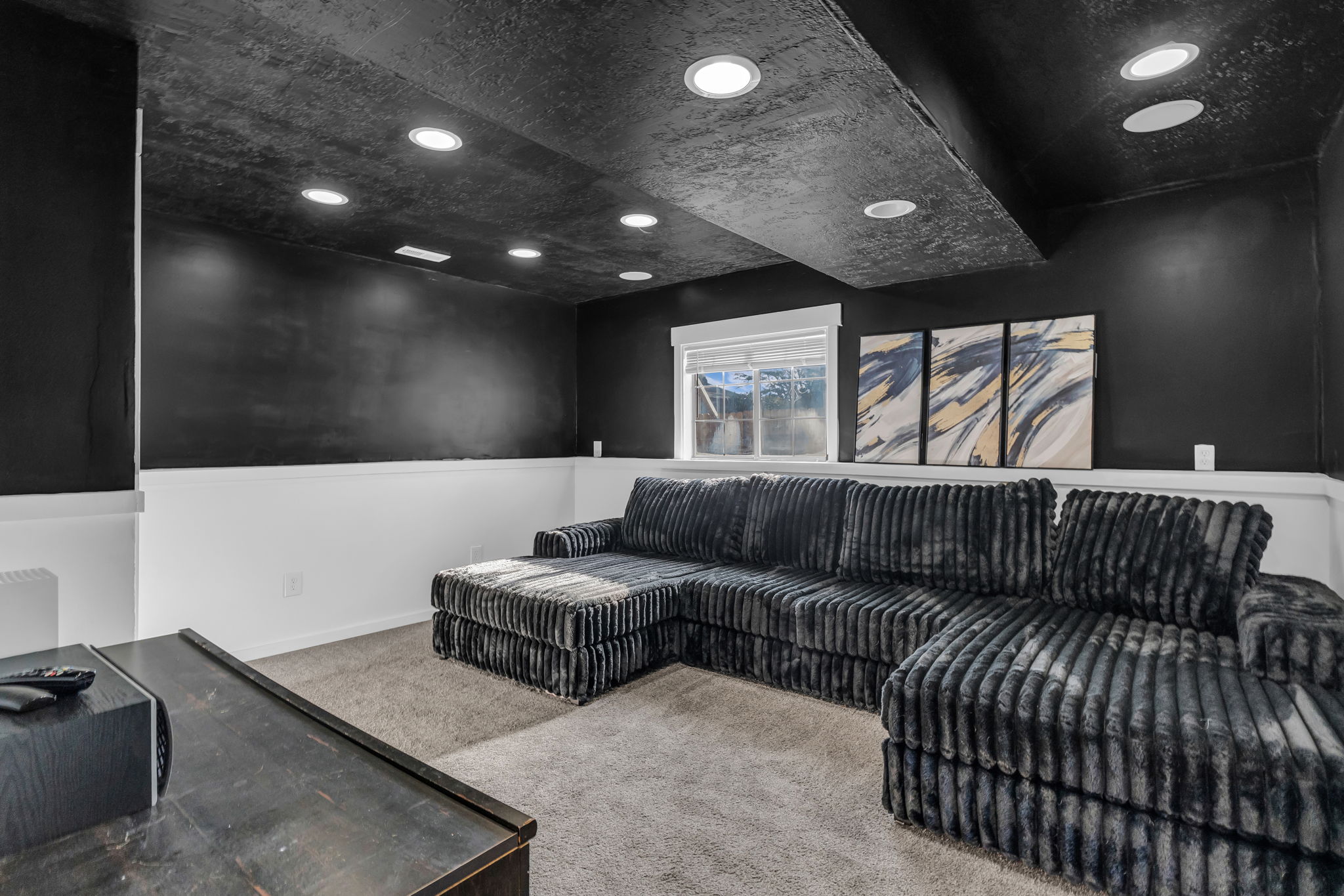 Recreation room featuring recessed lighting, a window with blinds, a two-tone wall treatment with a dark upper section, and a textured dark ceiling