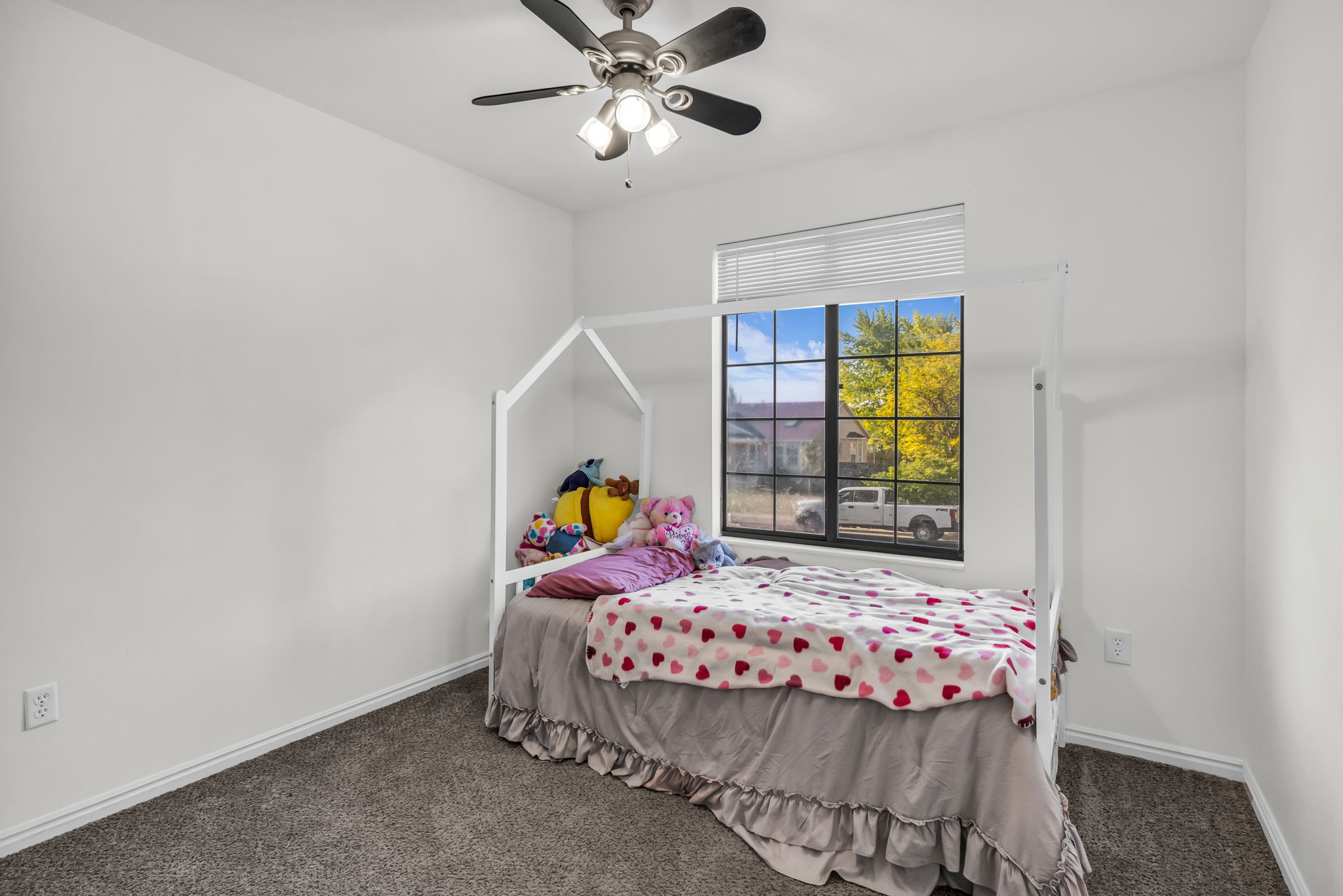 Neutral wall paint, textured carpet flooring, and a multi-pane window with blinds