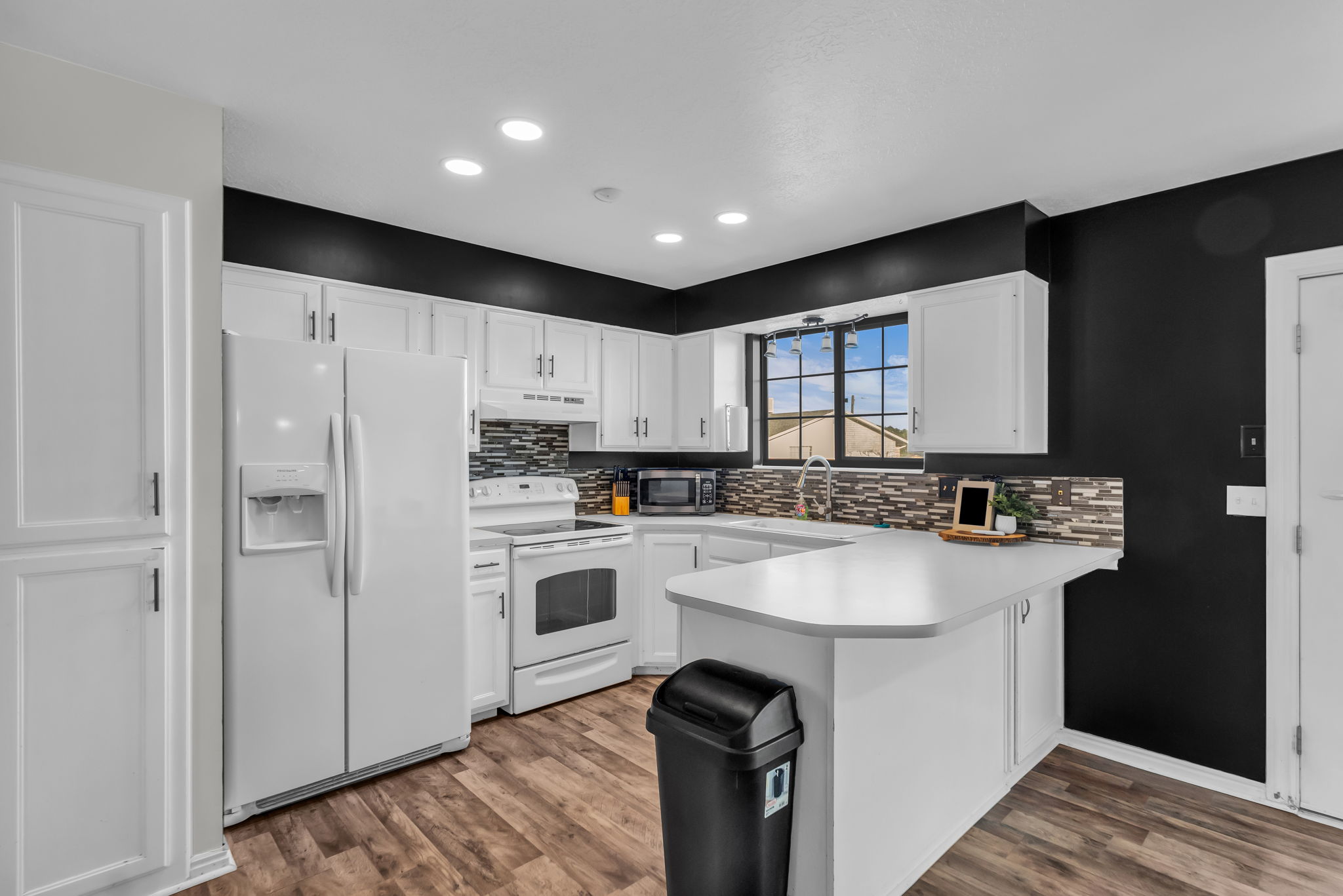 Kitchen featuring white cabinetry, wood-finish flooring, recessed lighting, and a window with grid detailing