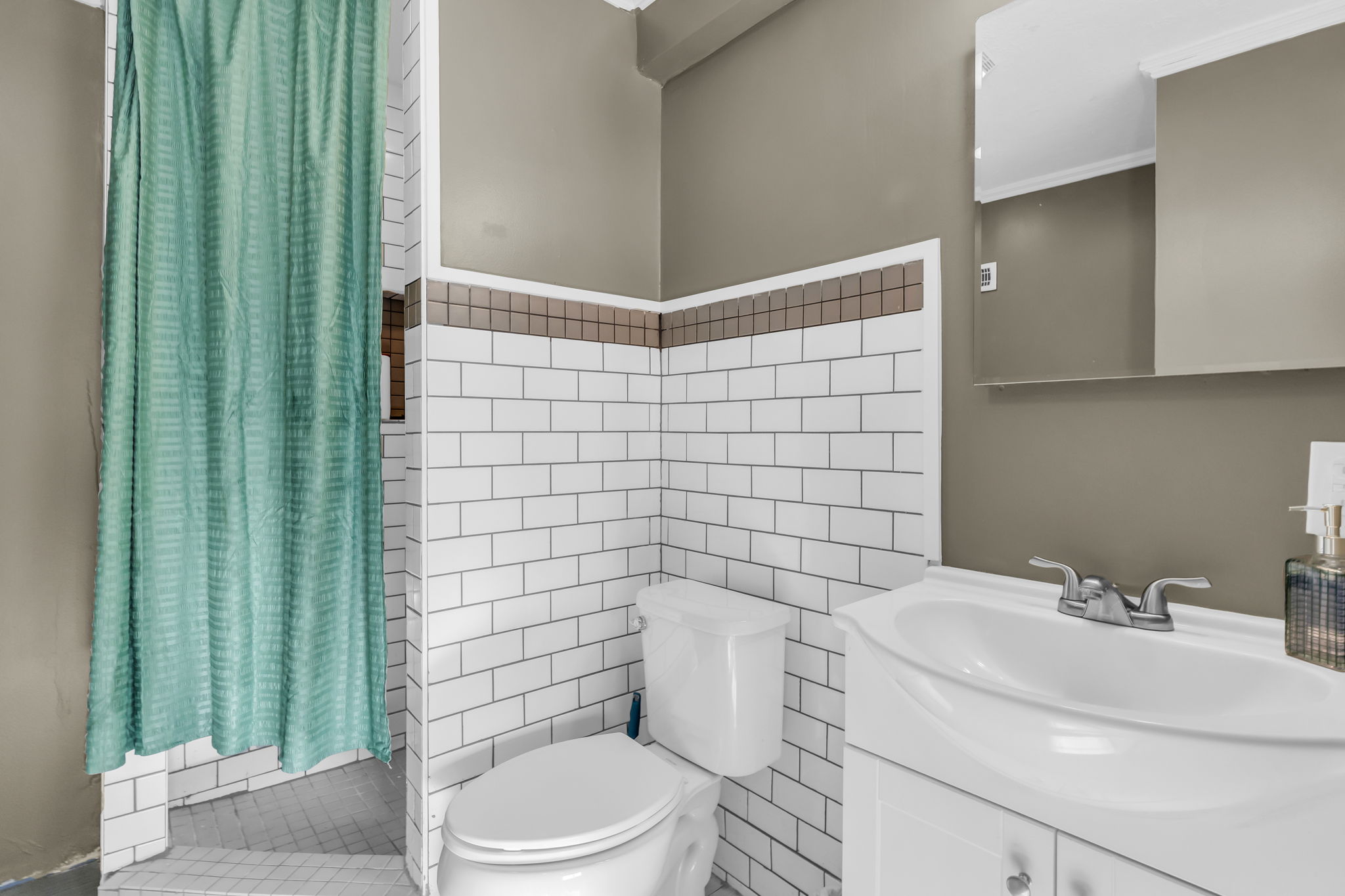 Bathroom featuring white subway tile wainscoting with a decorative accent border