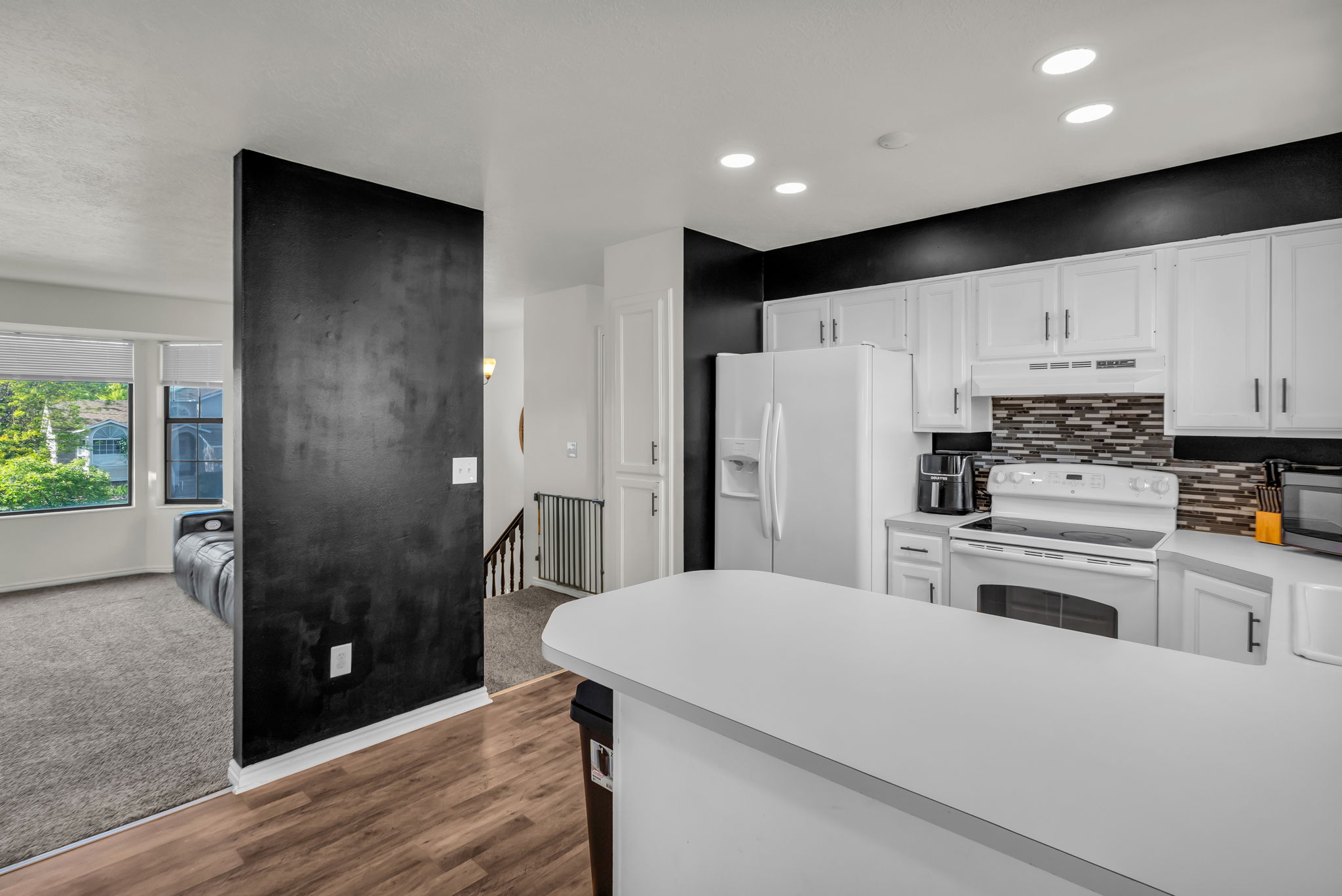 Kitchen featuring white cabinetry, a mosaic tile backsplash, and white appliances
