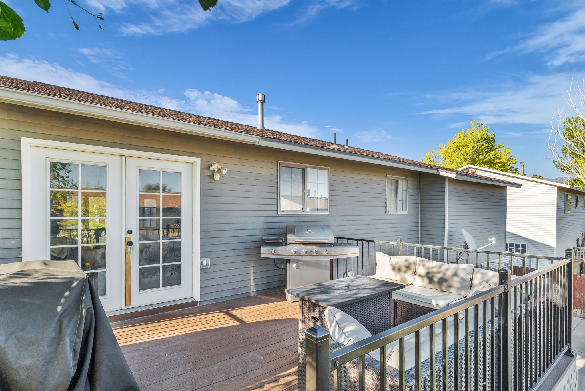 Spacious exterior deck featuring a dark wood-finish surface, white French doors, and black metal railings