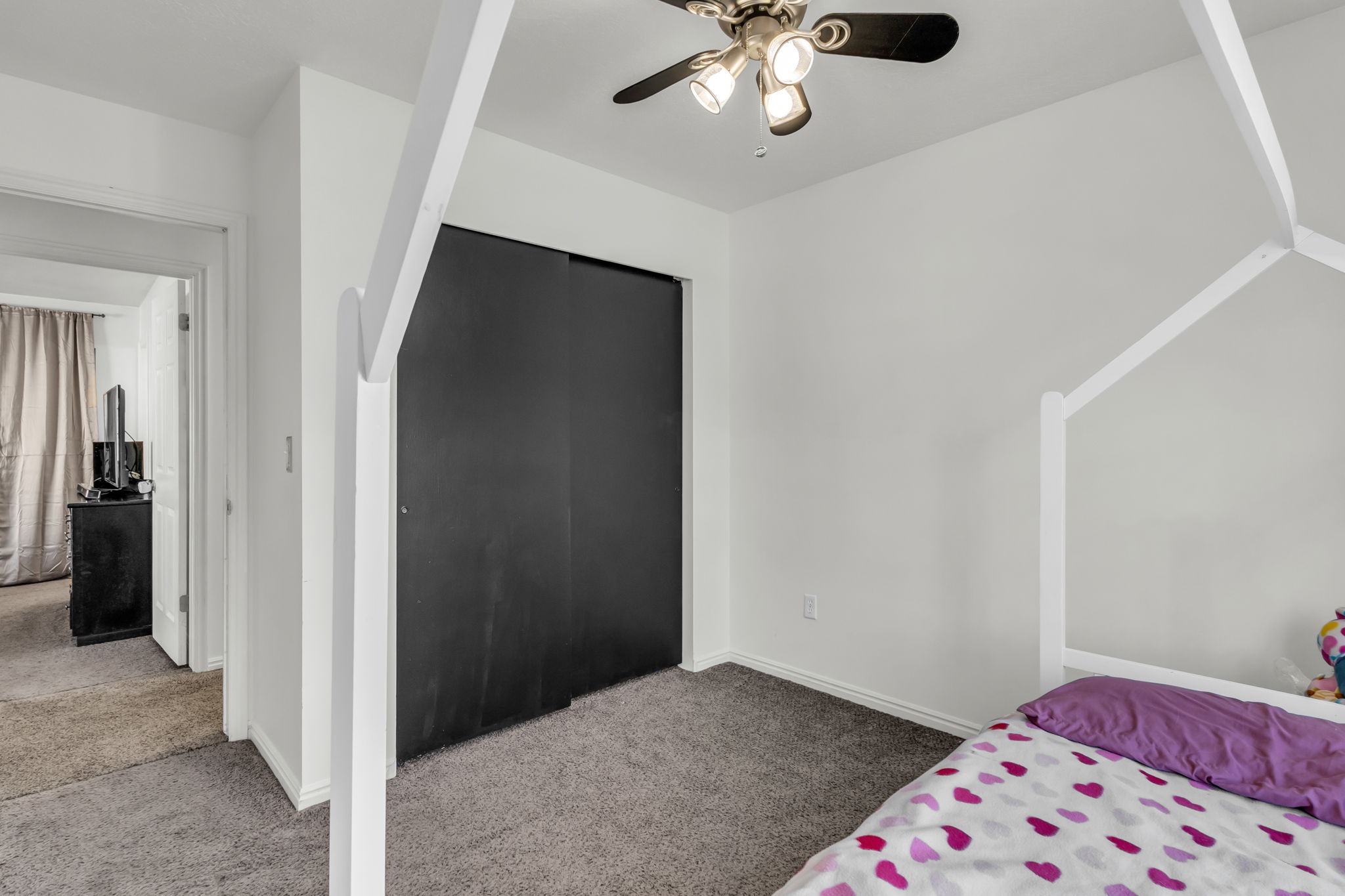 Bedroom featuring light gray carpeting, crisp white walls, and a ceiling fan with integrated lighting