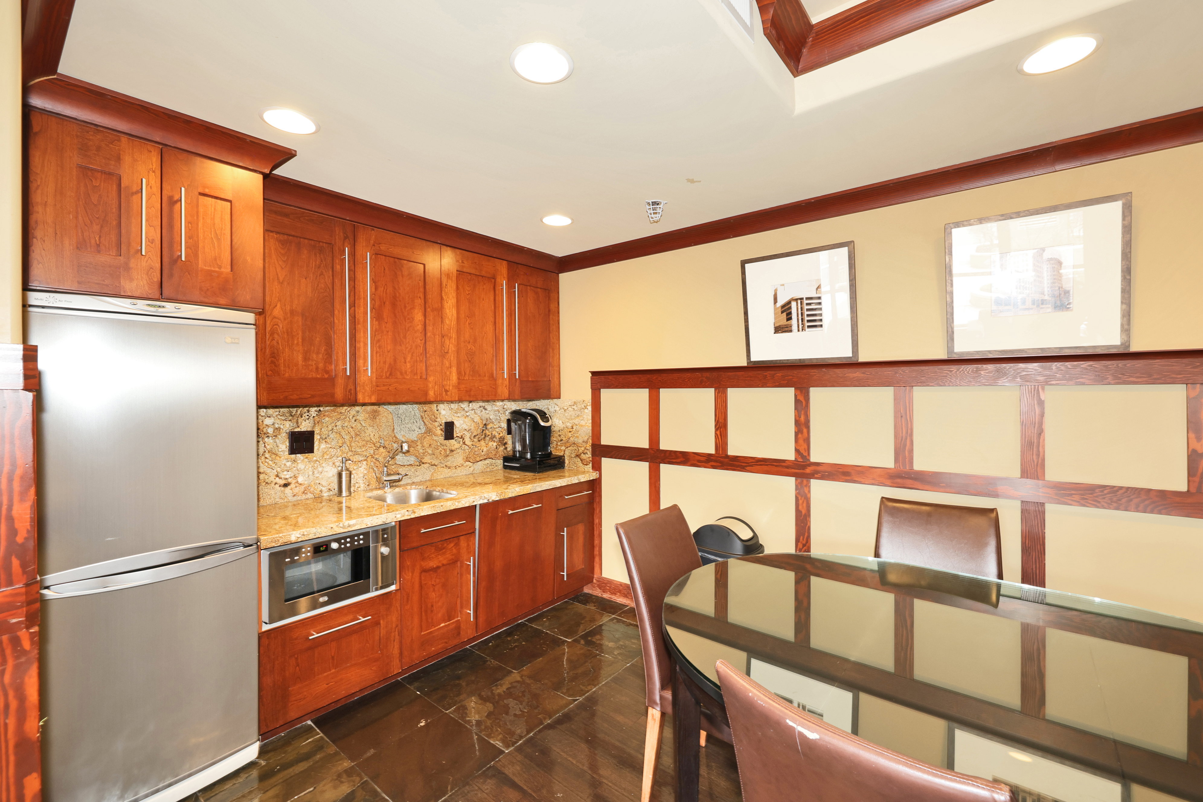 Built-in kitchenette featuring full-height cherry wood cabinetry, a stainless steel refrigerator, and a built-in microwave
