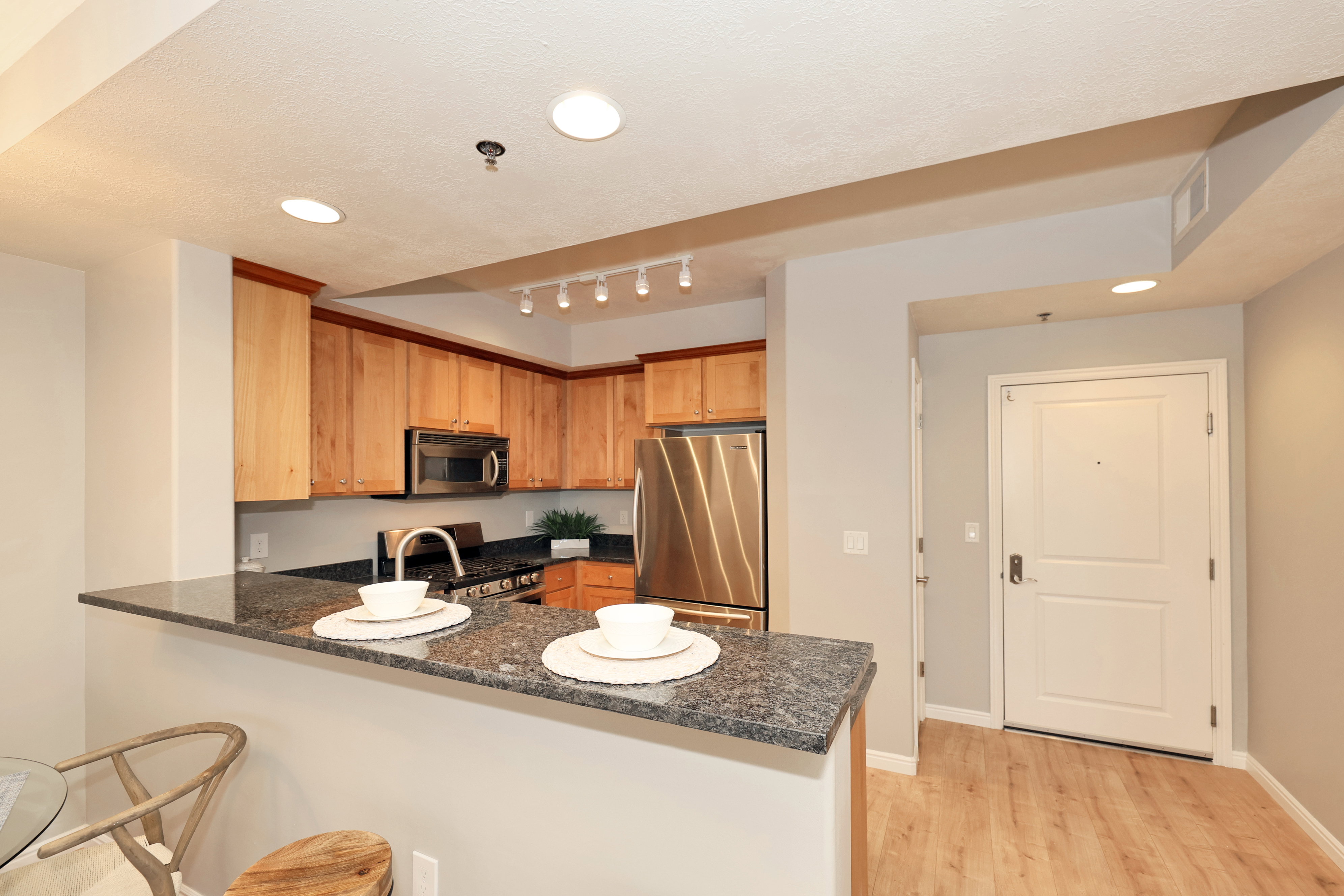 Kitchen featuring wood cabinetry, stainless steel appliances, a dark stone countertop, and an integrated breakfast bar