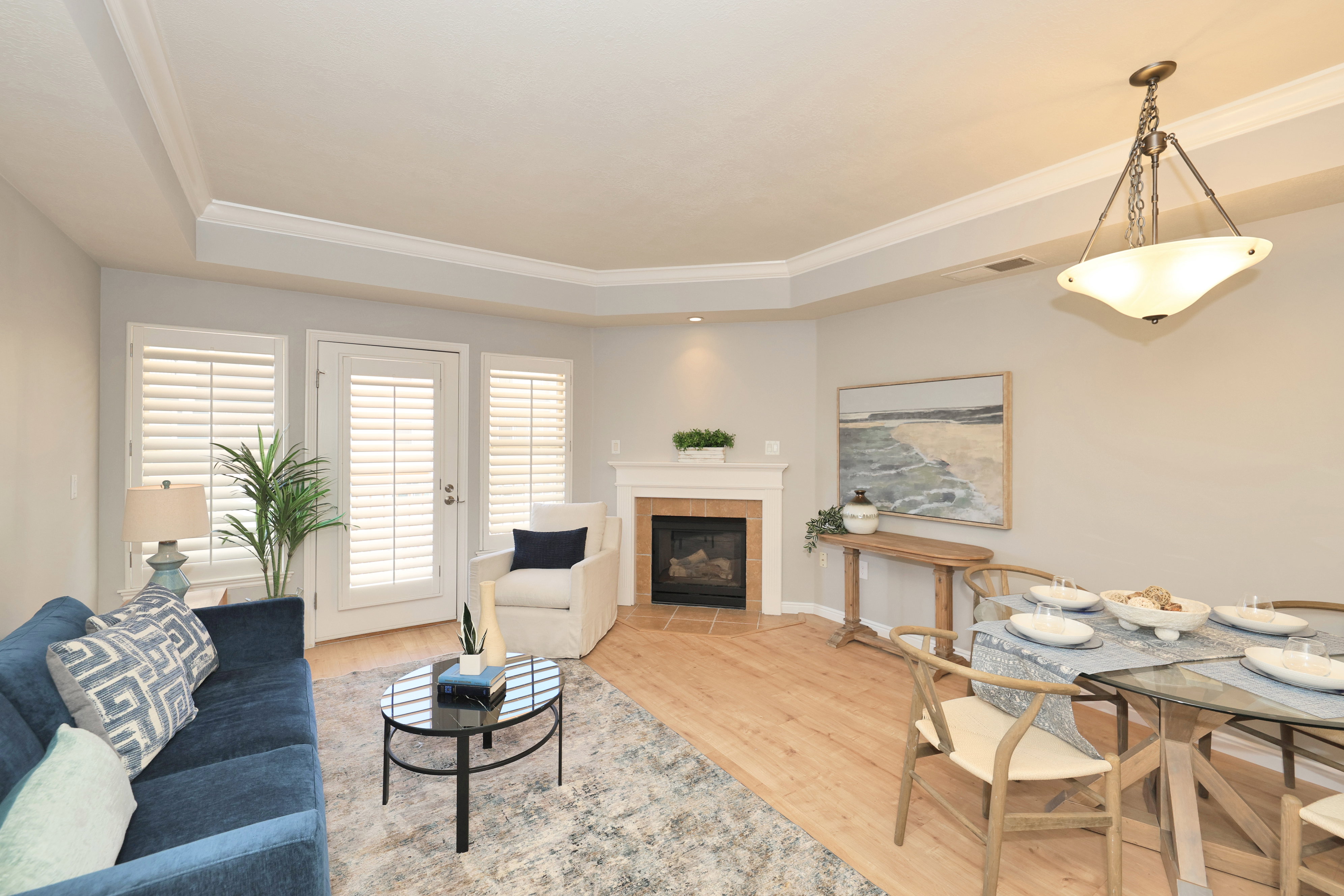 Open-concept living area with wood-finish flooring, crown molding, and a tray ceiling