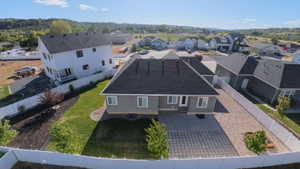 Rear exterior of a gray residence featuring a white privacy fence, a concrete patio, a gravel area, and a patch of green lawn