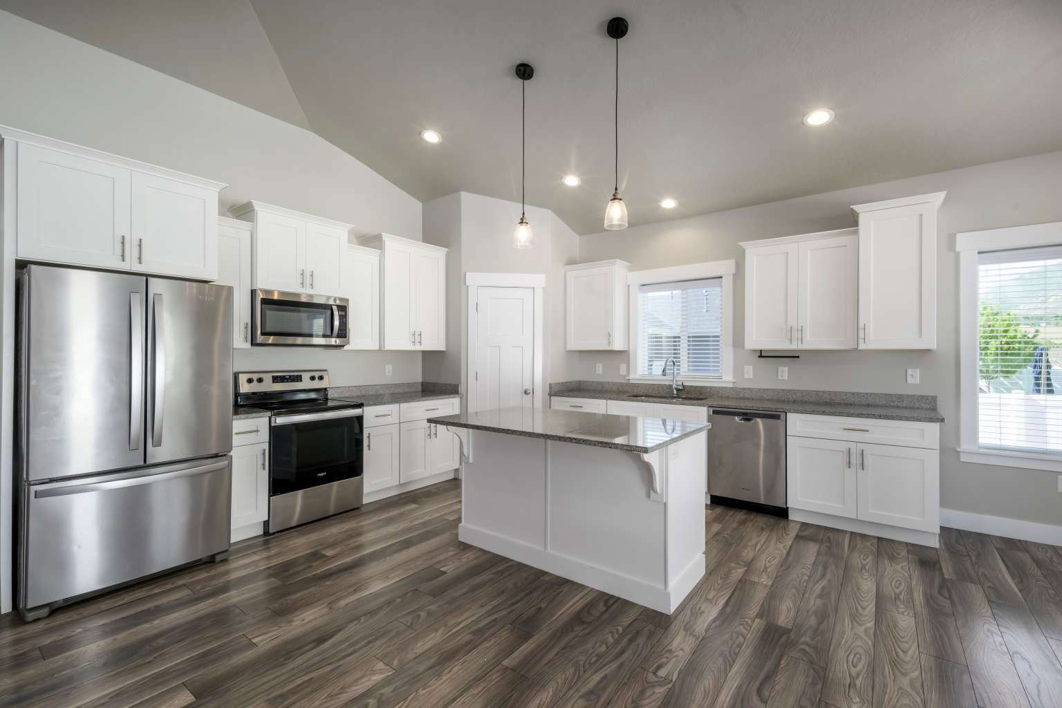Kitchen featuring stainless steel appliances, white cabinetry, a central island with countertop, wood-finish flooring, and recessed lighting