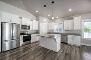 Kitchen featuring stainless steel appliances, white cabinetry, a central island with countertop, wood-finish flooring, and recessed lighting