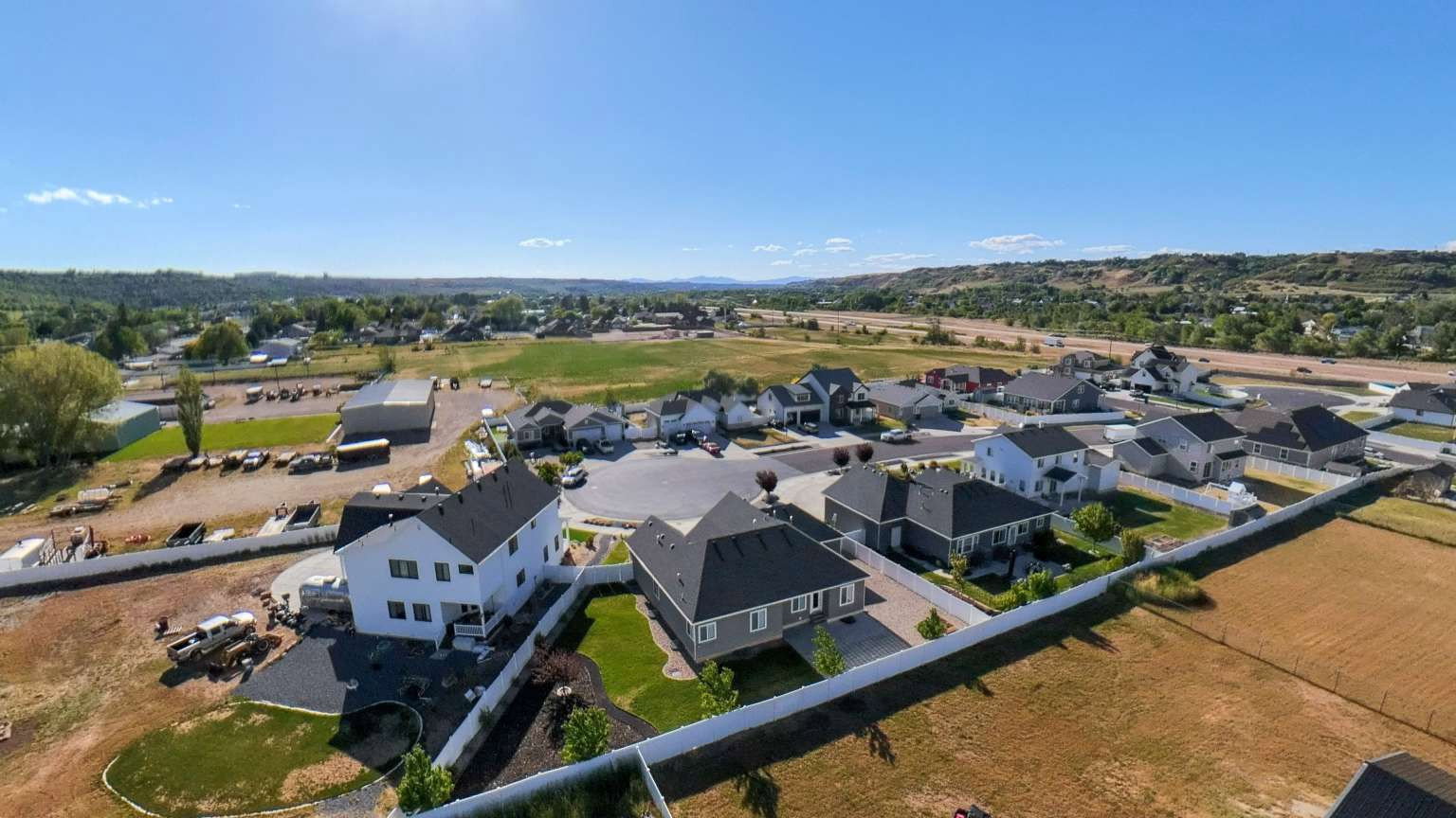 Aerial perspective showcasing a residential development with multiple single-family homes, each featuring dark-shingle roofing and light-toned siding