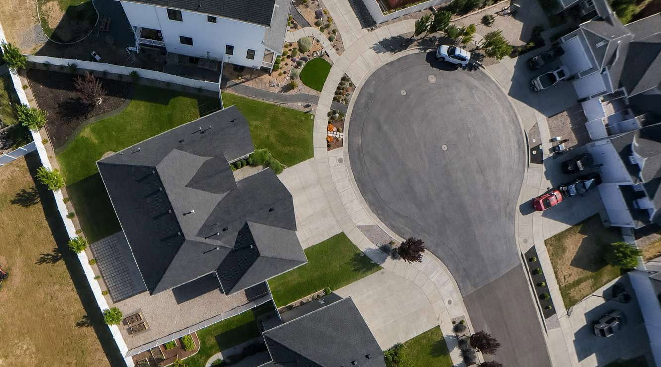 Property featuring a dark shingle roof, green lawn, and paver patio