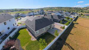 Newly constructed residence featuring a gray exterior with white trim, a dark shingle roof, and a gravel driveway