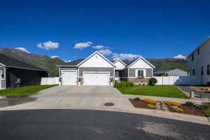 Modern ranch-style residence featuring a prominent two-car garage, gray horizontal siding, and white gable accents