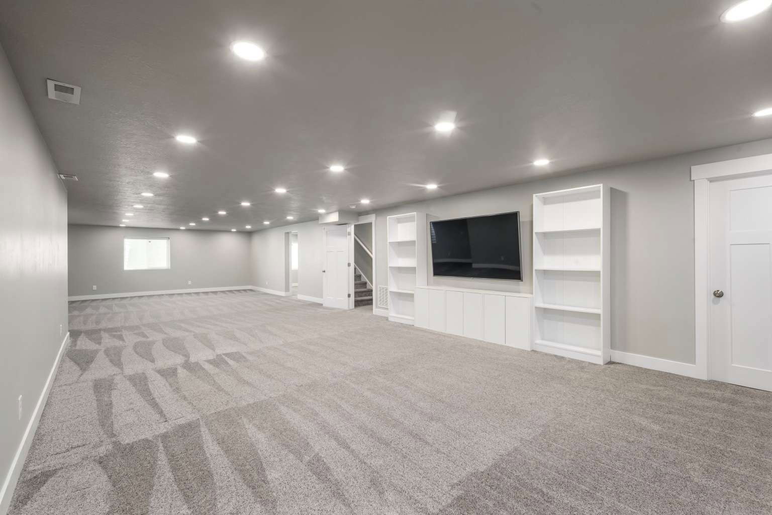 Spacious room featuring patterned gray carpet flooring, recessed lighting, and light gray wall paint