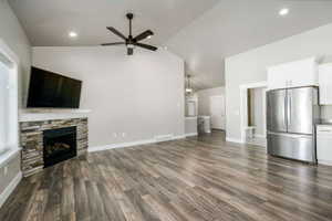 Spacious open-concept living area featuring wood-finish flooring, a vaulted ceiling, and recessed lighting