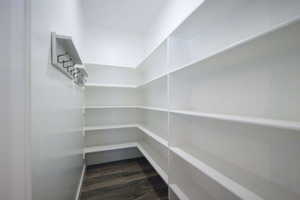 Walk-in pantry featuring extensive built-in shelving, wood-finish flooring, and a wall-mounted coat rack with multiple hooks