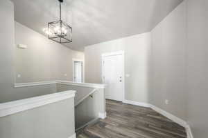 Entry foyer featuring wood-finish flooring, a contemporary black metal chandelier, and a white paneled entry door
