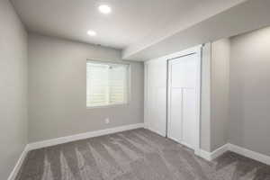 Room featuring gray carpeting, light gray walls, white baseboards, and a window with white horizontal blinds