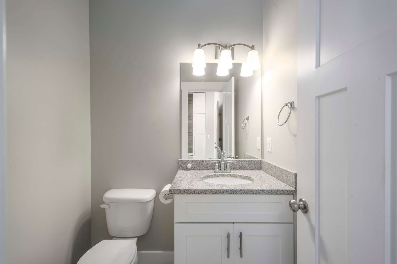 White vanity with a light-toned stone countertop and undermount sink