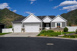 Contemporary ranch-style residence featuring a gray and white siding exterior with stone accents, a two-car garage, and a manicured front lawn