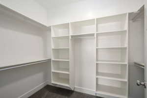 Walk-in closet featuring built-in shelving, white walls, dark gray carpet, and multiple hanging rods