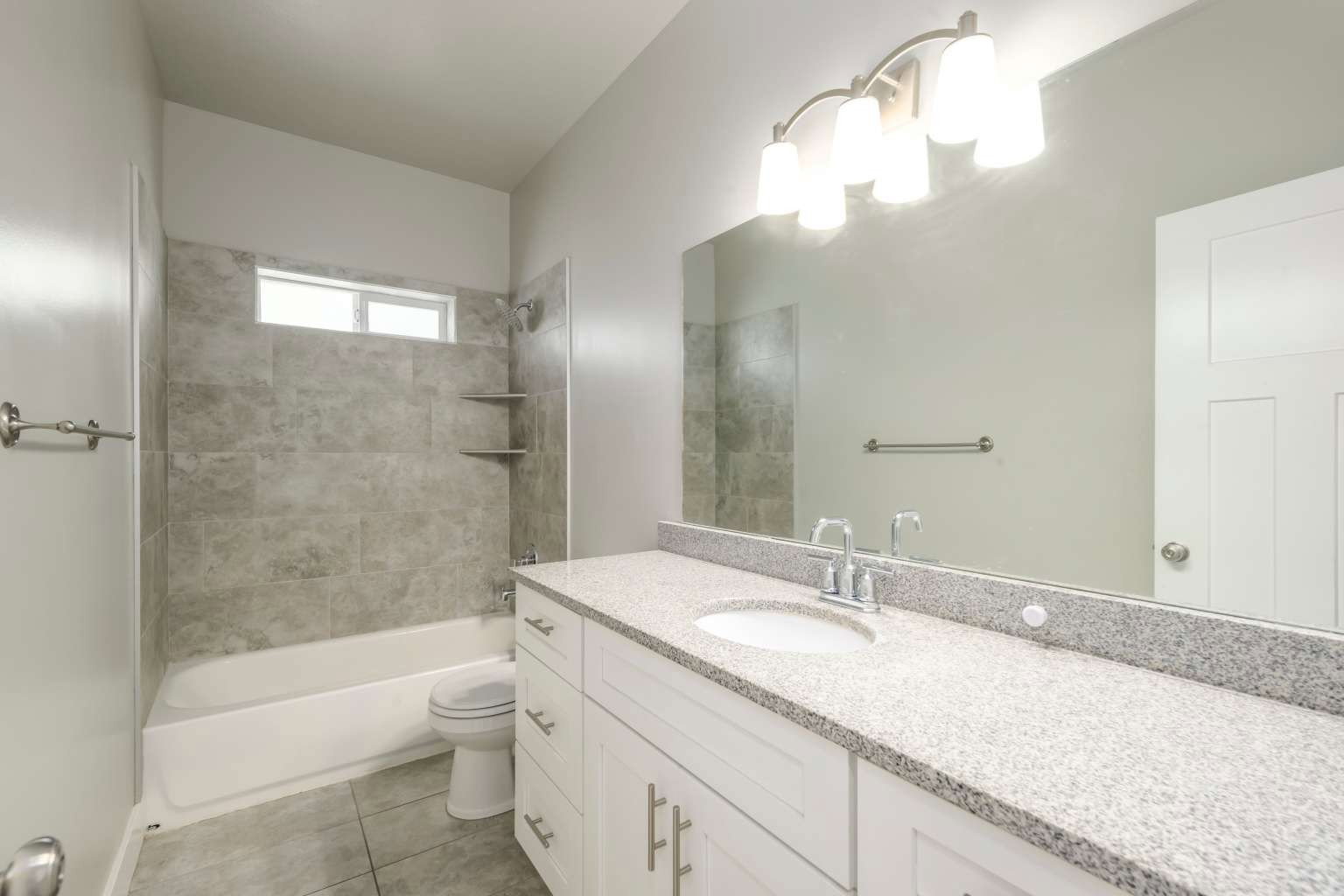 Bathroom featuring a white vanity with a light speckled countertop, an integrated sink, and an extended mirror