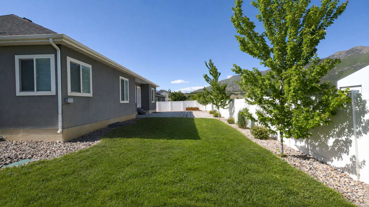 Expansive lawn bordered by a rock garden and mature trees
