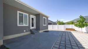 Exterior patio featuring concrete and paver sections, a white vinyl fence, and a raised garden bed