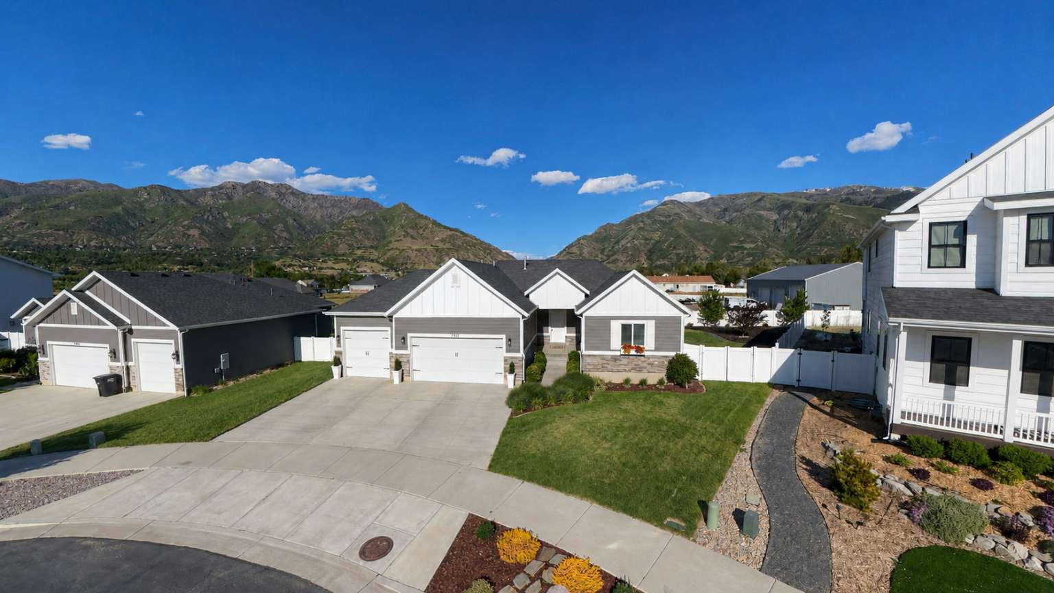 Modern ranch-style residence featuring a gray exterior with white trim accents and a dark roof