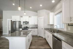 Kitchen featuring a central island with a granite countertop, white shaker cabinetry, stainless steel appliances, wood-finish flooring, and recessed lighting