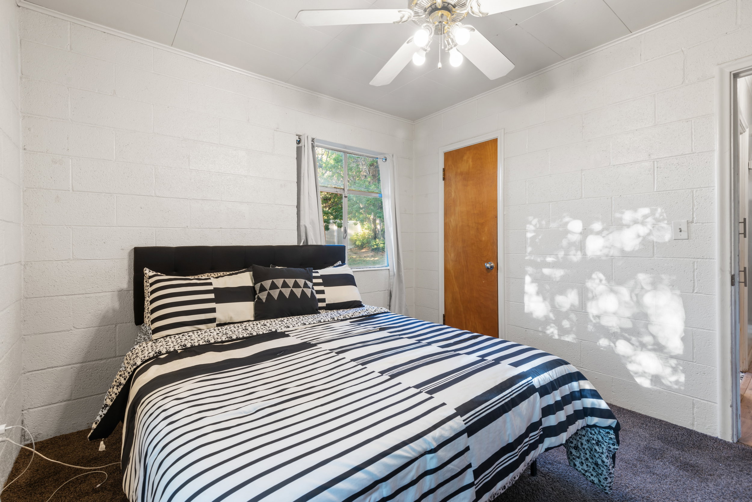 Bedroom featuring textured white block walls, dark carpeting, and a single window offering natural illumination