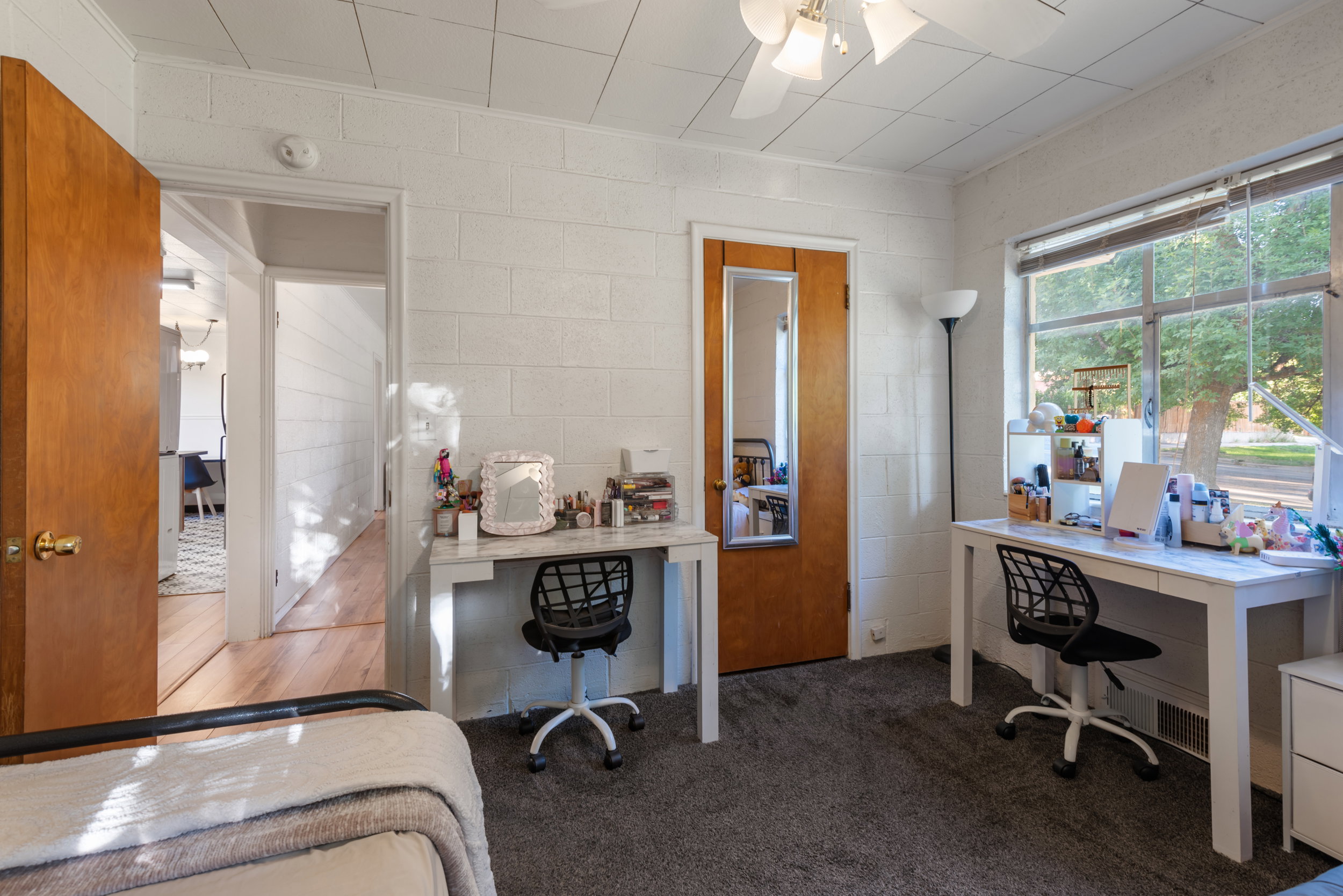Carpeted interior space featuring white block walls and a ceiling fan