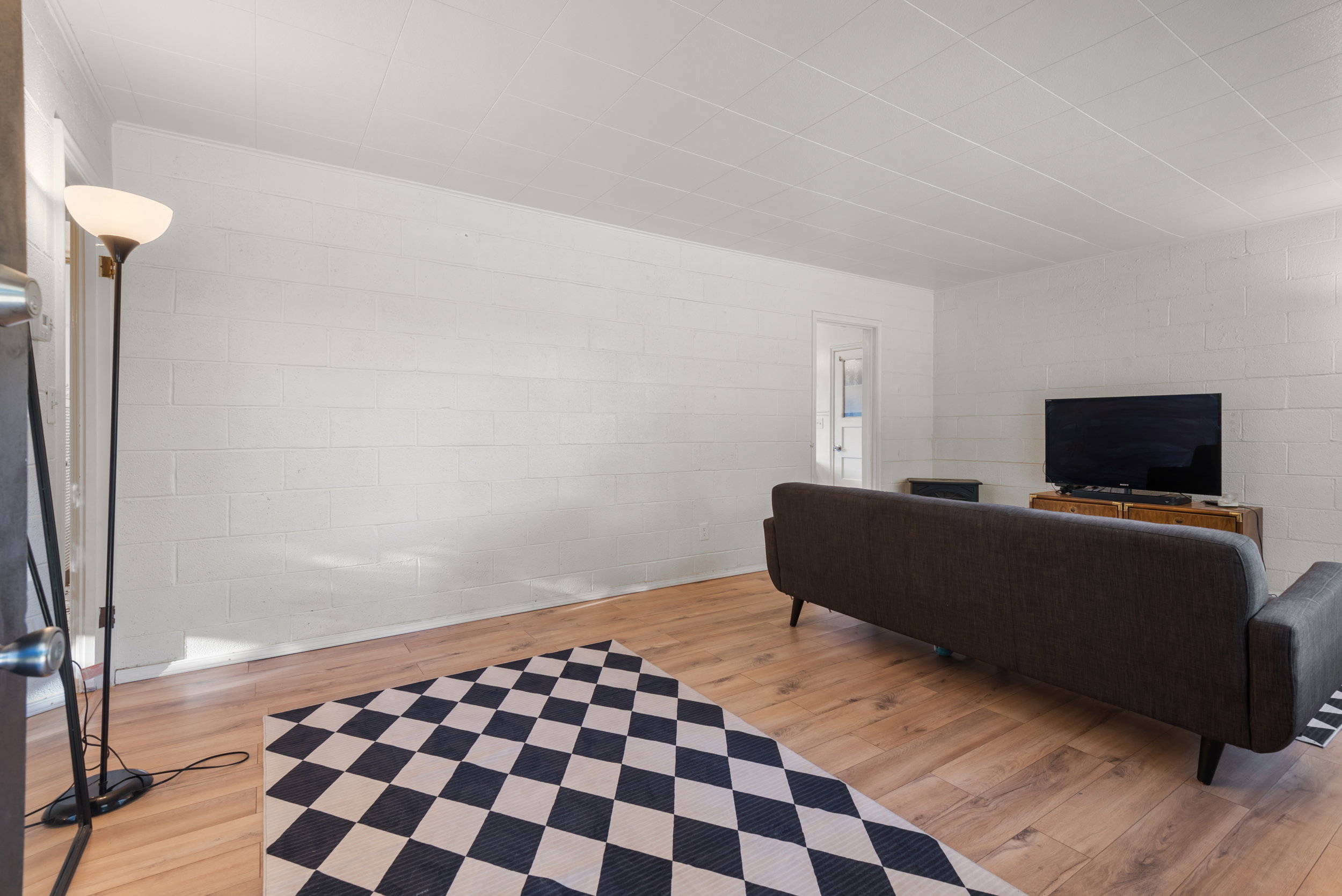 Spacious room featuring wood-finish flooring, white block walls, and a white ceiling