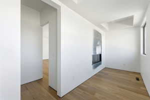 Interior space featuring wood-finish flooring, a recessed fireplace, and a window with black trim