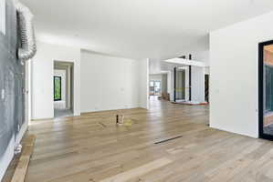 Expansive open-concept interior featuring light wood-finish flooring, white walls, and recessed lighting